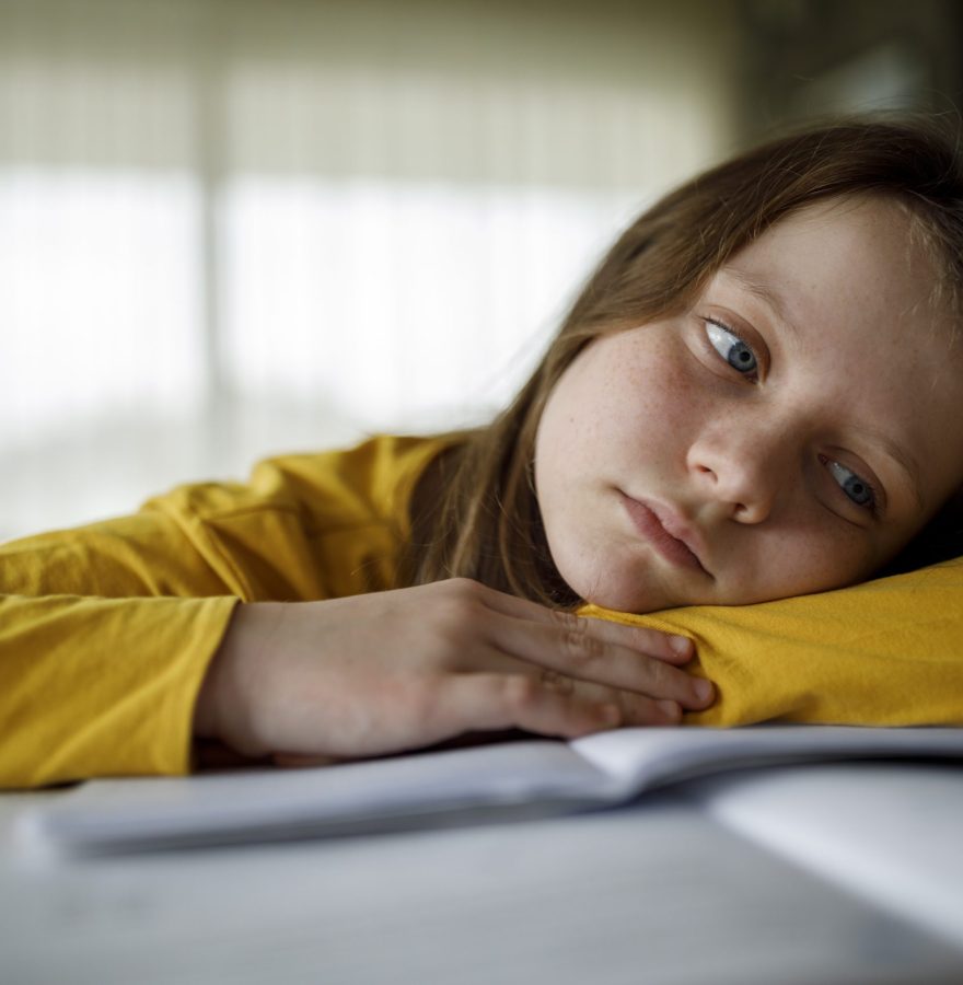 Bored young school girl studying at home