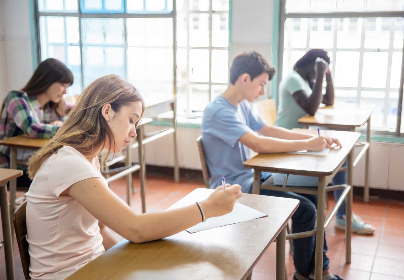 Group of multi ethnic high school students having test at classroom