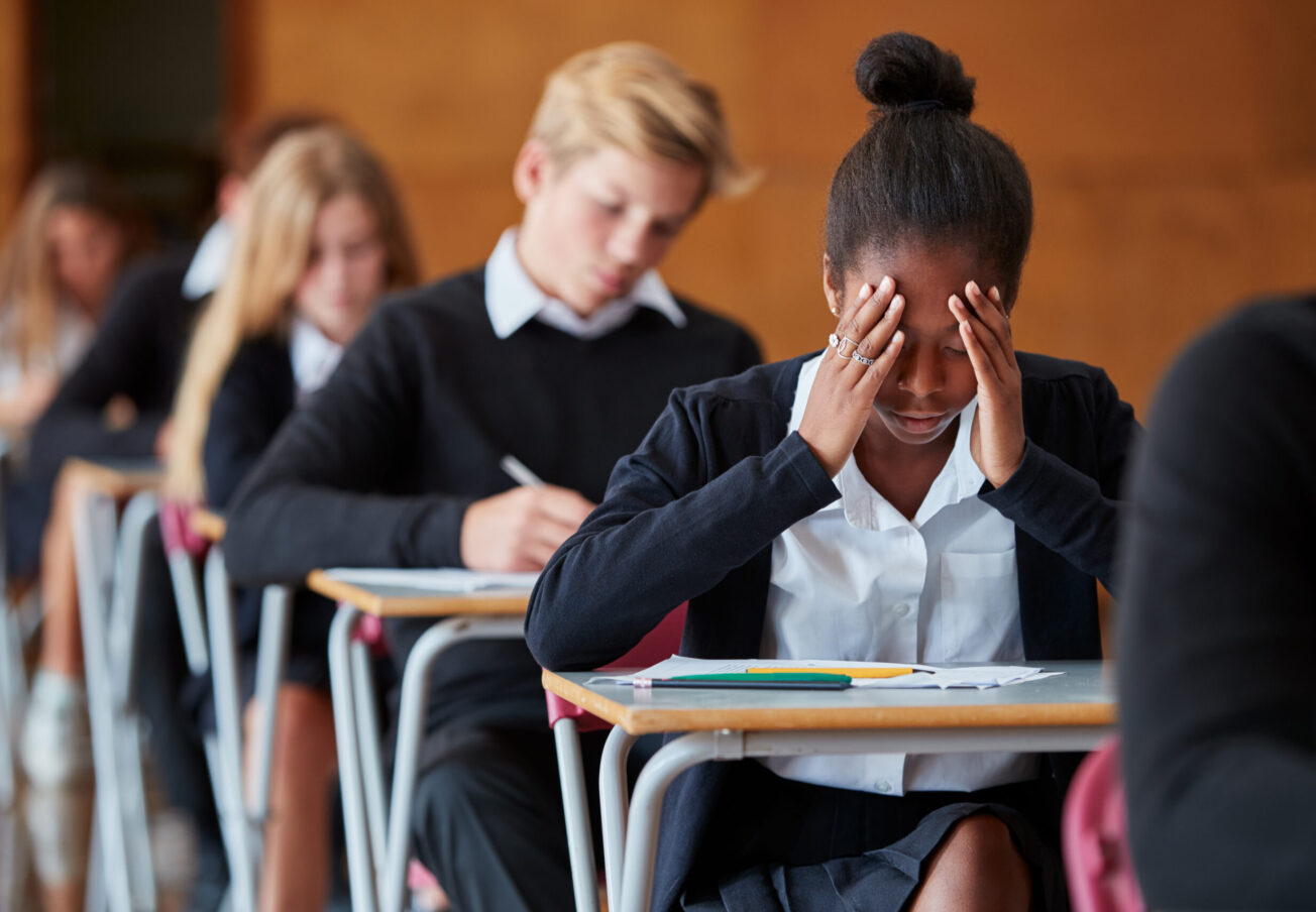 Anxious,Teenage,Student,Sitting,Examination,In,School,Hall
