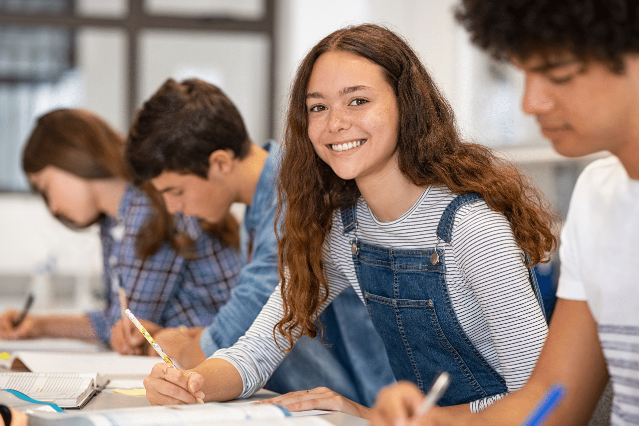 young teen girl smiling while doing school work at a therapeutic boarding schools